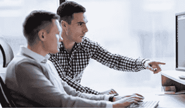 Two professionals discussing and pointing at a computer screen with software code.