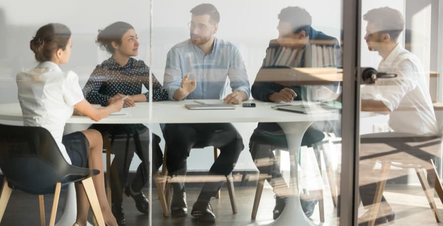 Data science professionals having a meeting around a desk.