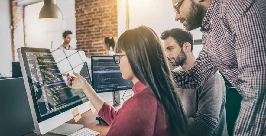 Three machine learning engineers working on some coding on a computer.