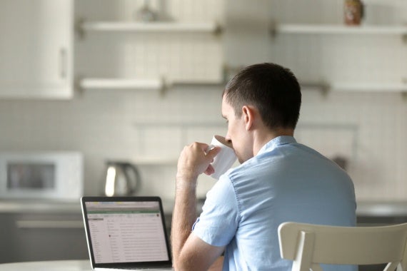 A university student sips coffee while studying at home.