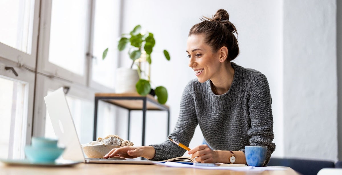 a smiling woman using laptop with career in finance