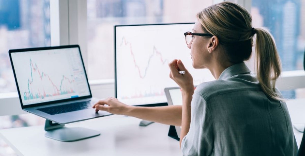 Woman analysing financial graphs and statistics on computer.