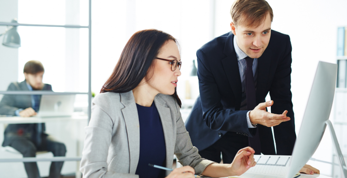 Man and woman reviewing work on a computer in a FinTech company office