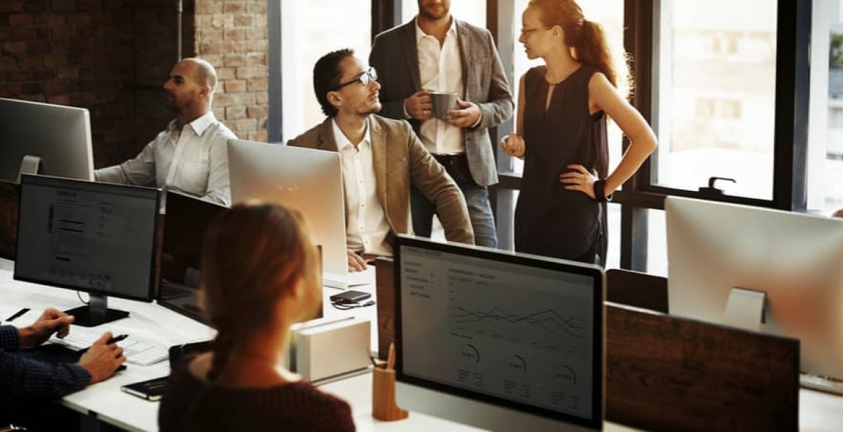 A data analyst works with a data visualisation program on a monitor in a busy office.