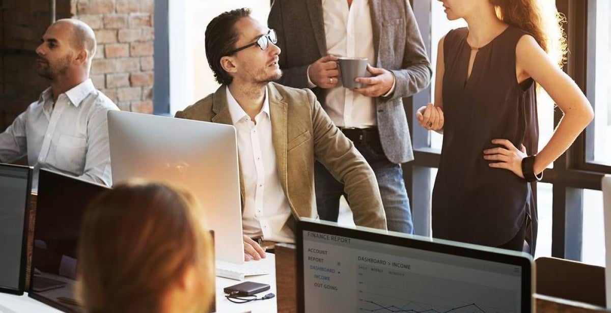 A data analyst works with a data visualisation program on a monitor in a busy office