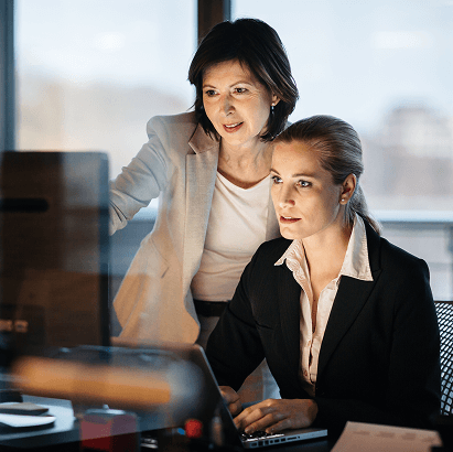 Two professionals working together at a computer in an office setting.