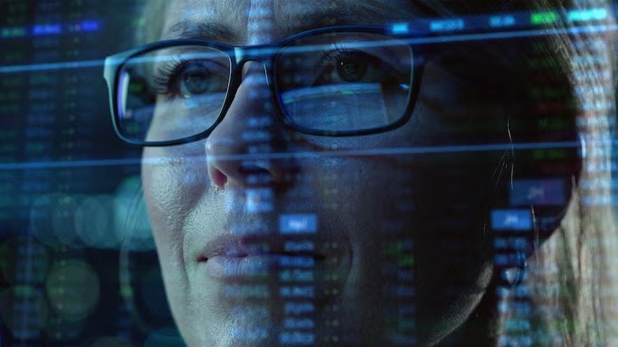 A woman with glasses focused on a computer screen, exploring cyber security salary trends and opportunities.