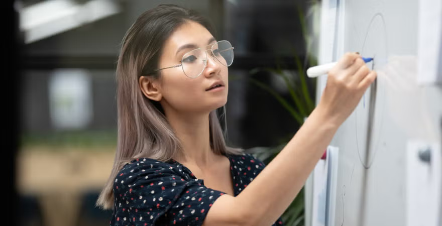 A female postgraduate student drawing a diagram on a whiteboard as part of the ADEPT learning approach