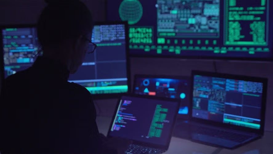 Cyber security professional working in front of computer monitors